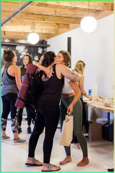 two women hugging each other in front of a group of people at a yoga class