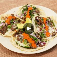 three tacos on a white plate topped with meat and veggies