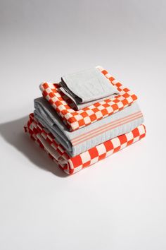 three folded towels are stacked on top of each other in different colors and patterns, one with a fork sticking out of it