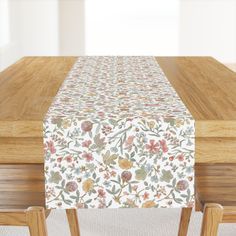 a wooden table topped with a white and red flowered table cloth on top of it