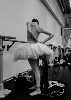 a woman in a tutu is standing on the floor with her hands behind her back