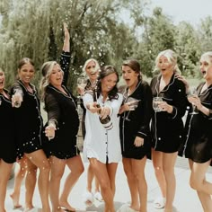 a group of women standing next to each other in front of a pool with confetti