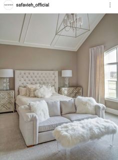 a large white couch sitting under a chandelier next to a bed in a bedroom