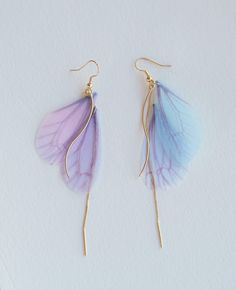 two pairs of earrings with purple and blue petals on them, hanging from gold hooks