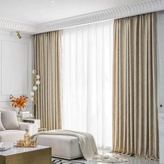 a living room filled with furniture and white walls in front of large window covered in drapes