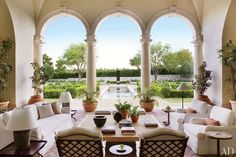 an outdoor living room with arches and potted plants