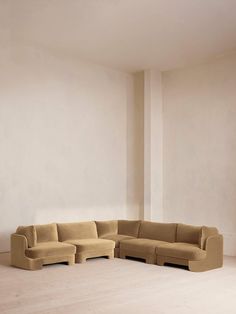 a living room with a large sectional couch in it's center and white walls