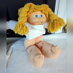 a doll with blonde hair sitting on a bed