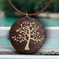 a wooden pendant with a tree on it sitting on a white bench next to a body of water