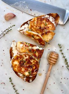 two pieces of bread with cheese and herbs next to a knife