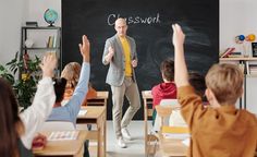 there is a man that is standing in front of the class room with his hands up