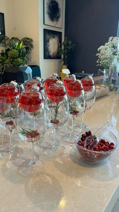 there are many wine glasses on the counter with red berries in them and one is empty