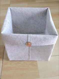 an empty gray felt box sitting on top of a wooden floor