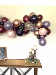 a table topped with balloons and candles next to a chalkboard