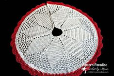 a crocheted doily with red and white trim around the edge on a black background