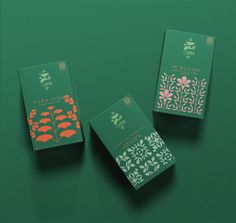 three green boxes with designs on them sitting next to each other in front of a green background