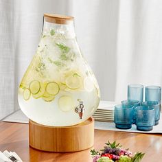 a pitcher filled with lemon slices and cucumbers on top of a wooden table