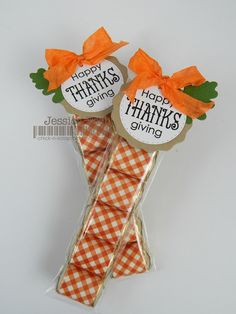 two candy sticks wrapped in orange and white paper with happy thanksgiving sayings on them