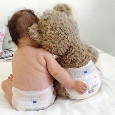 a baby in diapers is hugging a teddy bear