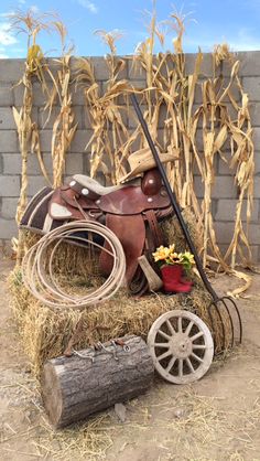 a hay bail with a saddle and flowers on it sitting next to a brick wall