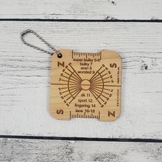 a wooden keychain that has a compass on it and is hanging from a chain