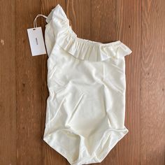 Mikoh Mini Swimwear Ray One Piece One Shoulder Swimsuit Girls Xl Nwt Off White / Bone Color One Shoulder Style With Ruffle Detail Will Be Shipped In Mikoh Clear Plastic Zip Pouch Summer Cotton Stretch Onesie, Stretch Bodysuit For Playwear, Summer Stretch Bodysuit For Playwear, Spring Beach Fitted Onesie, Fitted Sleeveless Summer Onesie, Fitted Beach Onesie For Summer, Summer Beach Fitted Onesie, Fitted Cotton Onesie For Beach, Summer Onesie For Playwear, Fitted