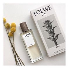 a bottle of loewe oil next to some flowers and a box on the table