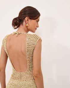 the back of a woman's dress that is crocheted with gold thread