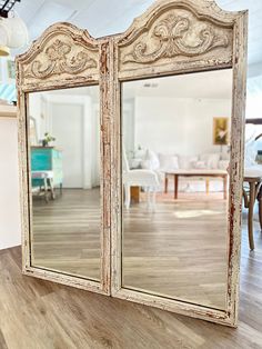 an old white mirror sitting on top of a wooden floor next to a dining room table