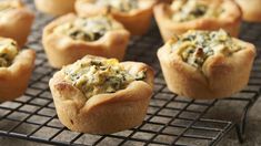 several muffins on a cooling rack with spinach and cheese in the middle