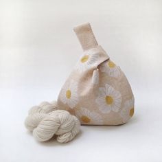 two balls of yarn sitting next to a bag with flowers on it's side