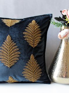 a gold and black pillow next to a vase with flowers