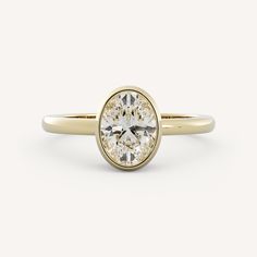 a yellow gold ring with an oval cut diamond in the center