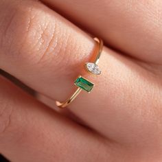 a woman's hand with a gold ring and green stone on top of it