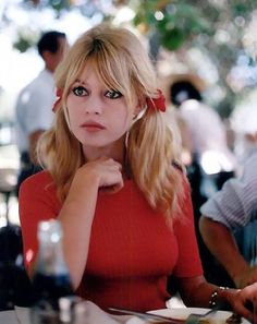 a woman sitting at a table with her hand on her chin looking to the side