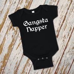 Gangsta napper infant bodysuit/ hip hop baby clothes/ funny old school rap baby romper baby shower gift infant snap suit featuring Gansta Napper in old English font. White will be printed on some color garments and black will be printed on other colors. If you are concerned with which color printing will be on which color garment, please inquire. 100% combed ringspun cotton fine jersey Heather gray is 93/7 jersey Taped shoulder-to-shoulder with EasyTear™ label Reinforced three snap closure Hip Hop Gender Reveal Ideas, Hip Hop Baby Shower Ideas, Hood Rap Shirts, Biggie Smalls Shirt Baby, Punk Rock Baby Clothes, English Fonts, Funny Baby Clothes, Old English Font, Old English