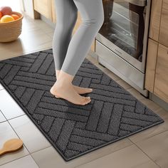 a woman in grey leggings is standing on a kitchen mat next to an oven