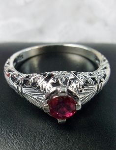 <> Made To Order This is a Victorian/Edwardian reproduction ring in sterling silver filigree with a natural red ruby gemstone solitaire. This full cut round cut red ruby gemstone is 4mm in diameter. The inside of the band is marked 925 for sterling. Notice the beautiful floral design of the silver filigree setting and band. This is a lovely rendition of an Antique filigree ring, and it is ready to wear. A gift ring box is included and all rings are shipped in the ring box for safekeeping. Antique Engraved Ring With Intricate Design In Sterling Silver, Antique Sterling Silver Engraved Ring With Intricate Design, Vintage Engraved Ring In Antique Silver For Wedding, Victorian Engraved Rings For Marriage, Vintage Ceremonial Engraved Ring With Intricate Design, Sterling Silver Victorian Filigree Ring, Silver Rings With Historical Design As Gift, Victorian Filigree Ring With Intricate Design In Sterling Silver, Vintage Sterling Silver Filigree Ring With Intricate Design