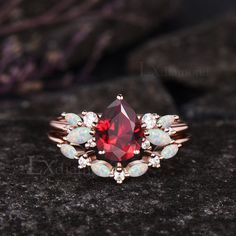 a close up view of a ring with red and white opal stones on it