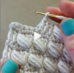 a person holding a crochet hook in their right hand and knitting it on the other