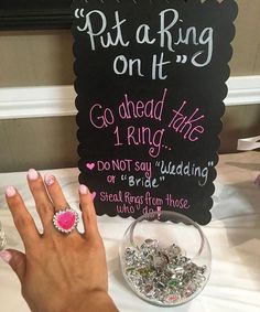 a woman's hand with pink and white nails next to a sign that says put a ring on it