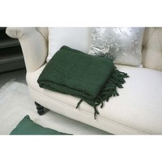 a green blanket sitting on top of a white couch