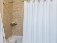 a white shower curtain in a bathroom next to a bath tub