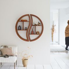 a woman is walking past a wall with shelves on it