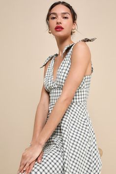 Life is like a picnic when you look oh-so-cute in the Lulus Sweetest Posture Navy and Cream Gingham Tie-Strap Midi Dress With Pockets! Lightweight cotton-blend fabric, with a darling gingham print in hues of cream and blue, falls from tying sash straps into a flattering surplice neckline (and back) and a fitted bodice with gathered details. The high, banded waist sits atop a twirl-worthy, skater skirt that features side seam pockets and finishes at a timeless midi hem. Hidden side zipper/clasp. 50s Housewife Dress, 50s Housewife, Housewife Dress, Gingham Midi Dress, Midi Dress With Pockets, Surplice Neckline, A Picnic, Gingham Dress, Gingham Print