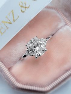 a close up of a diamond ring in a velvet case with a name tag on it