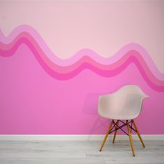 a white chair sitting in front of a pink wall with waves painted on the walls