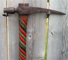 an old, rusty hammer stuck into a wooden fence with colored ropes attached to it