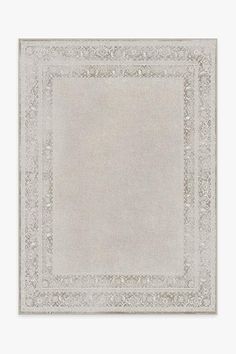 a white rug with an ornate border in the middle and a light gray background on top