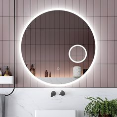 a bathroom with a round mirror on the wall and a plant in front of it